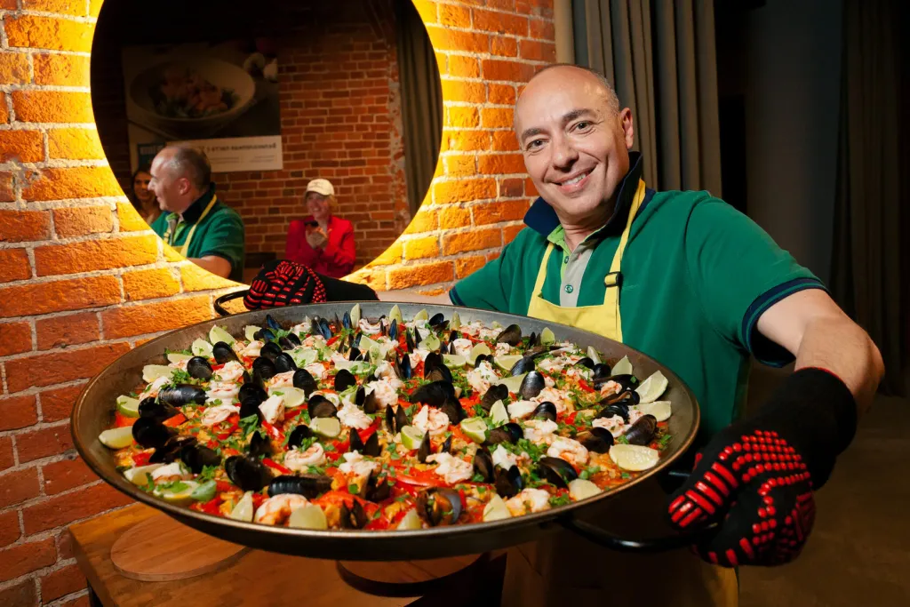 Мастер-класс для мужчин в CulinaryOn — участник показывает большую сковороду с паэльей