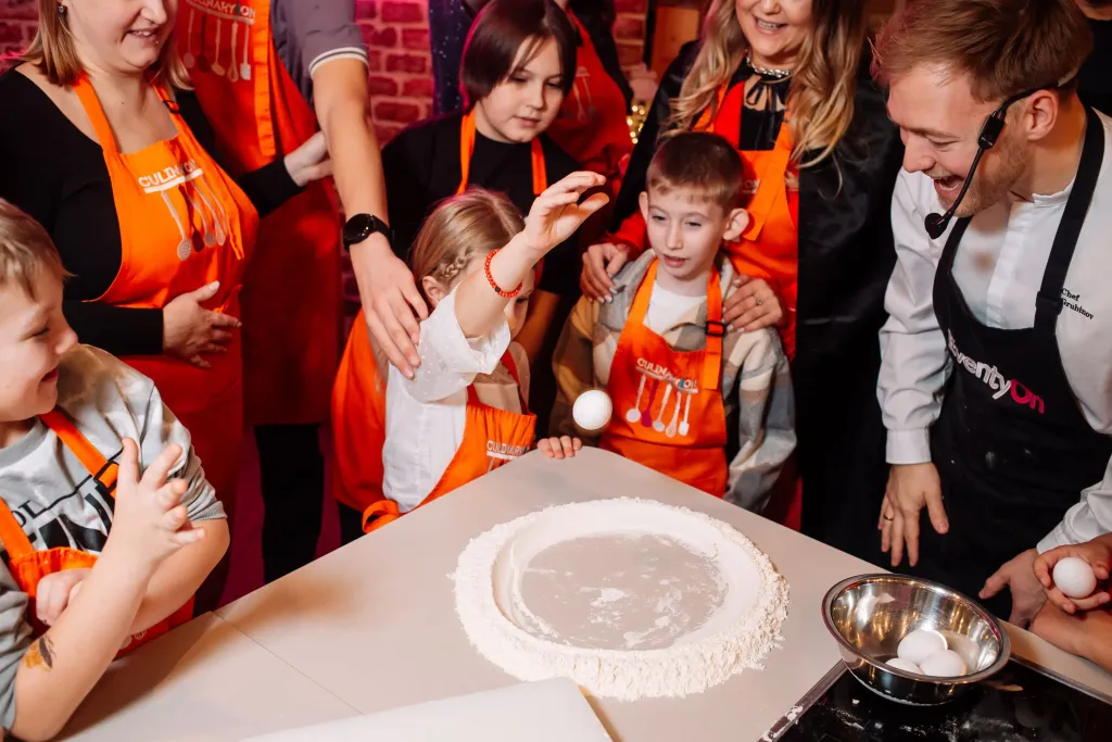 Мастер-класс по приготовлению пиццы для детей в CulinaryOn — ребёнок разбивает яйцо в муку под руководством шефа
