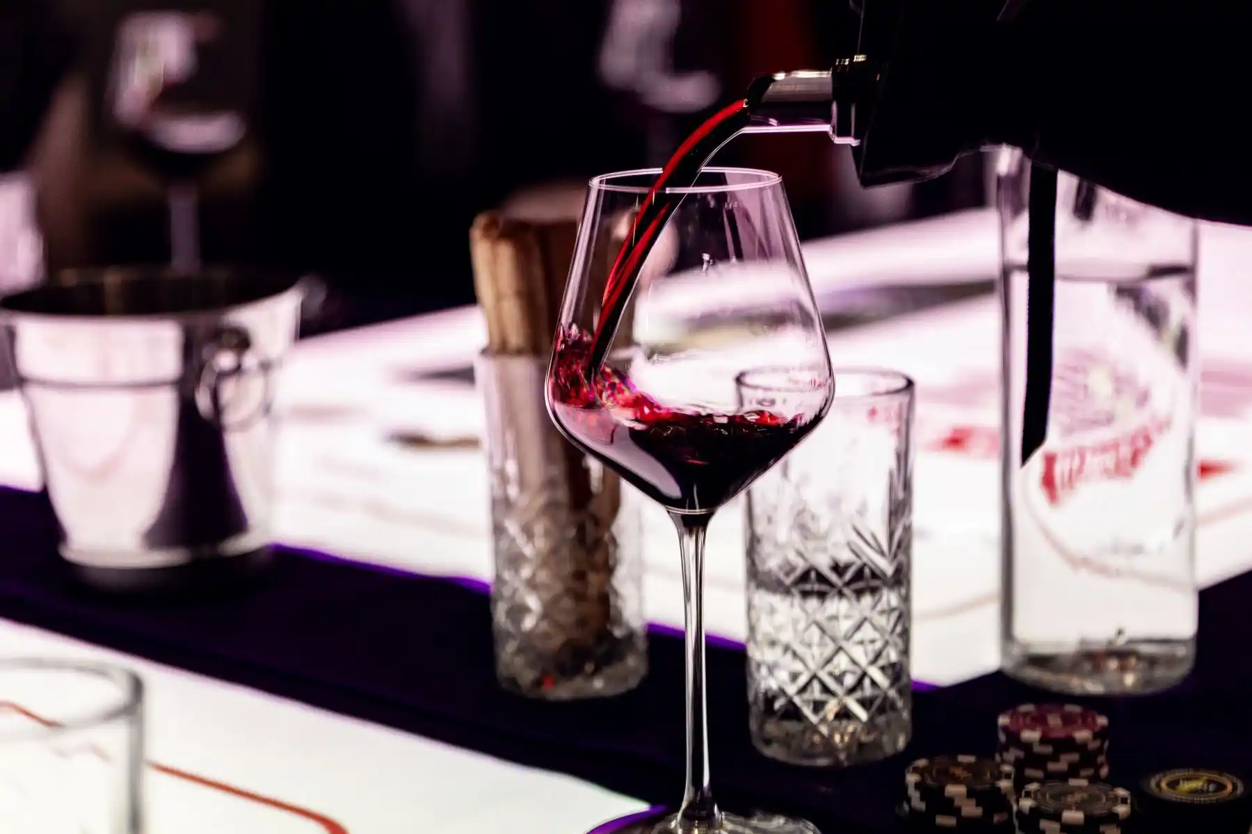 Винное казино (18+) — сомелье наливает красное вино в бокал